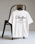 Hoodies Liban white oversized Turkish cotton t-shirt with black Badbee studio logo print on the back hanging on a chair
